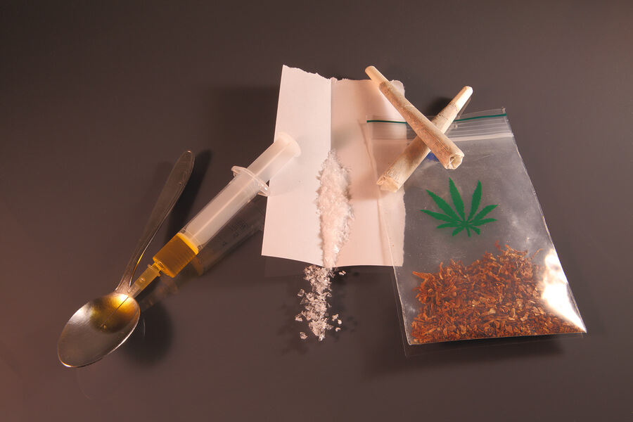 Needle, syringe, white crystals and joint as a symbol for drugs